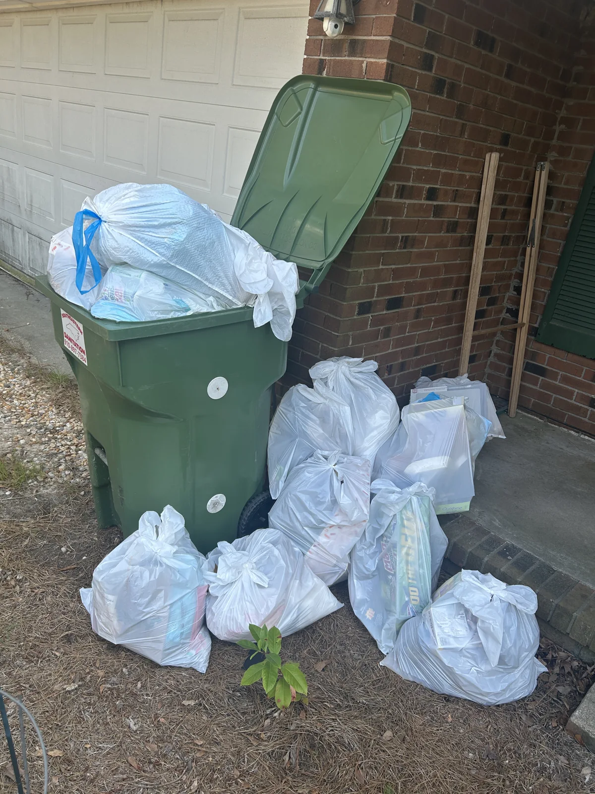 Bagged household junk overflowing beside a bin before ACG’s pickup